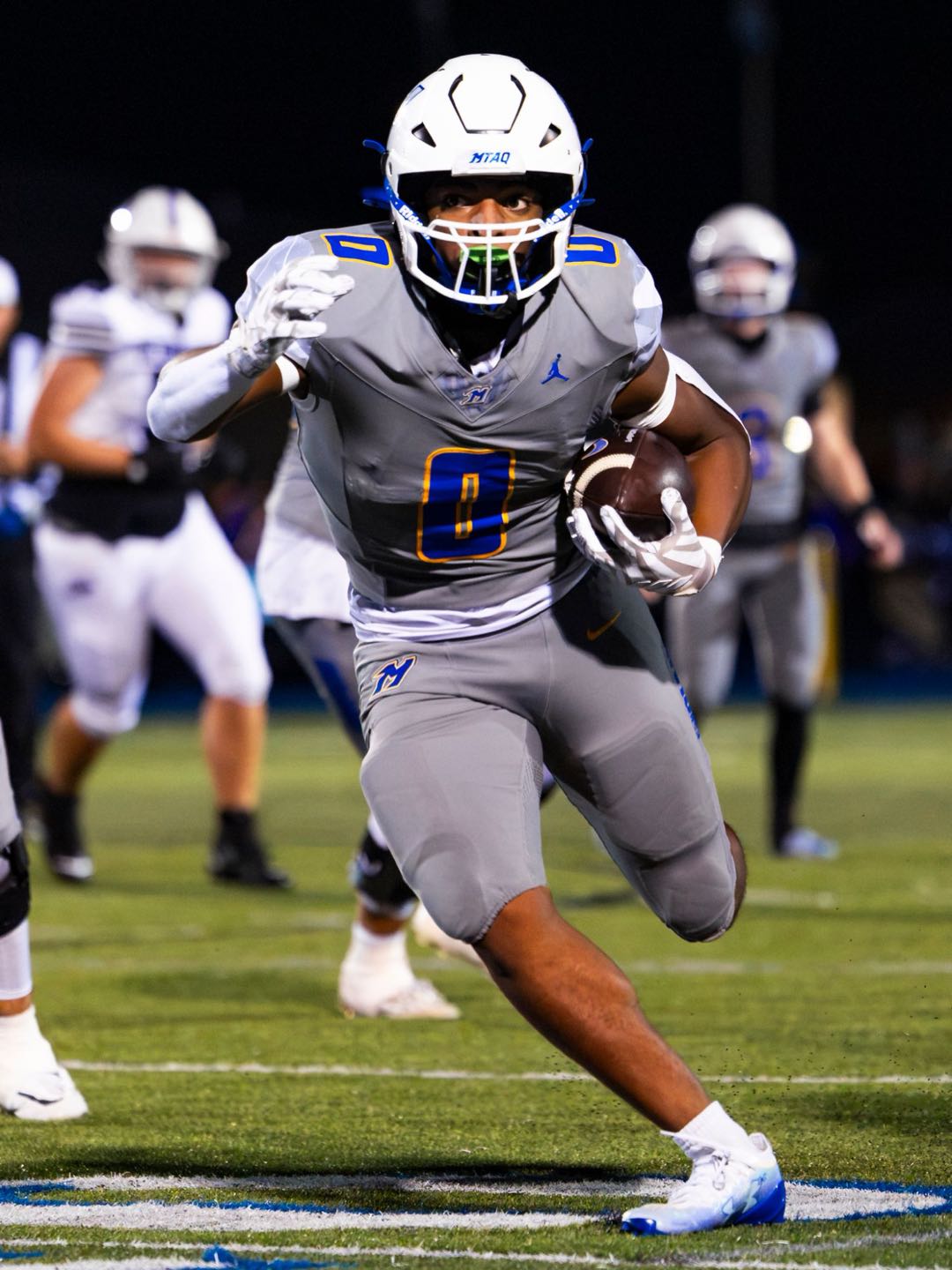 Mukwonago’s number 0 running the ball at a night game