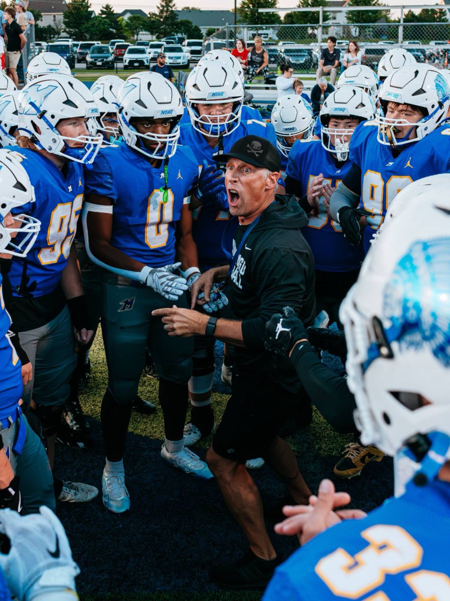 A coach firing up the Mukwonago football team in a pregame huddle